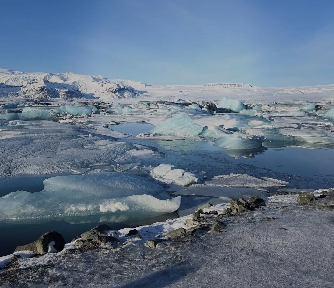 A rental car parked along Iceland's Ring Road with icebergs from Jökulsárlón visible across the water